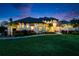 Stunning exterior shot of a modern home with lush landscaping, palm trees, and a beautiful lawn at twilight at 2662 Delphi Hills Ct, Lakeland, FL 33812