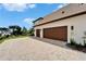 View of the three-car garage and a brick paved driveway of this beautiful home at 2662 Delphi Hills Ct, Lakeland, FL 33812