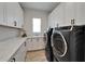 This spacious laundry room features white cabinets, countertops, and modern washer and dryer at 2662 Delphi Hills Ct, Lakeland, FL 33812