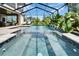 Sparkling pool with a waterfall feature, screened enclosure, and lush tropical landscaping at 2662 Delphi Hills Ct, Lakeland, FL 33812