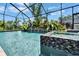 Screened-in pool and spa with lush landscaping and a clear blue sky above at 2662 Delphi Hills Ct, Lakeland, FL 33812