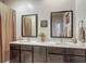 Bathroom featuring double sinks, framed mirrors, brown cabinetry, and neutral décor at 2683 Corvette Ln, Kissimmee, FL 34746