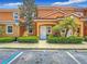 Inviting two-story condo with an orange exterior, lush landscaping, and handicap parking at 2683 Corvette Ln, Kissimmee, FL 34746