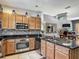 Well-lit kitchen featuring stainless steel appliances, granite countertops, and wood cabinets at 2683 Corvette Ln, Kissimmee, FL 34746