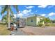 Light green home featuring a brick paved driveway, palm trees, and a parked trailer at 3016 Wood Duck Dr, Polk City, FL 33868