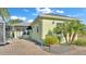 Charming light green home with brick paved driveway, black awning, and well-kept landscaping at 3016 Wood Duck Dr, Polk City, FL 33868