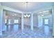 Open-concept layout with neutral tile flooring, columns, and modern chandelier at 4019 Tullamore Ln, Auburndale, FL 33823
