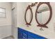 Bathroom featuring double sinks, bright blue vanity, decorative mirrors, and neutral tile flooring at 402 W Patterson St, Lakeland, FL 33803