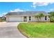 Charming single-story home with a well-manicured lawn, palm trees, and a driveway leading to an attached garage at 404 Willow Run, Lakeland, FL 33813