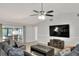 Bright and airy living room featuring tile floors, ceiling fan, entertainment center and a sliding glass door at 404 Willow Run, Lakeland, FL 33813