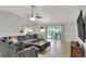 Cozy living room showcasing tile floors, large gray sectional seating, and access to outdoor dining area at 404 Willow Run, Lakeland, FL 33813