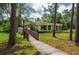 Exterior view of the home with a ramp, well-manicured lawn, and mature trees surrounding the property at 409 San Jose Dr, Winter Haven, FL 33884
