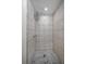 Bathroom shower featuring white tile walls and floor with marble mosaic drain area at 409 San Jose Dr, Winter Haven, FL 33884