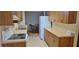 Galley kitchen with wooden cabinets, a white refrigerator, and a dining area with natural light at 5211 Berkley Rd, Auburndale, FL 33823