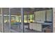 View of the covered patio featuring a screened enclosure, table, chairs, and appliances at 5211 Berkley Rd, Auburndale, FL 33823