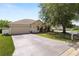 View of a one-story home with beige siding, a well-manicured lawn, and a two-car garage at 5733 Oakwood Knoll Dr, Lakeland, FL 33811