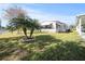 Bright home featuring manicured lawn, a carport, and decorative palm trees at 6087 Southern Oaks Se Dr, Winter Haven, FL 33884