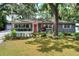 Charming one-story home boasts a well-maintained lawn, mature trees, and an inviting orange front door at 618 W Oak Dr, Lakeland, FL 33803