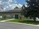 Exterior view of the community clubhouse with an American flag, front lawn, and palm tree lined sidewalk at 6194 Sanderling Dr, Lakeland, FL 33809