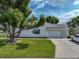 Home exterior with garage, green lawn, and mature tree at 6194 Sanderling Dr, Lakeland, FL 33809