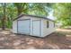 Exterior view of a white storage shed with a roll up door and standard door at 6527 Fernwood Dr, Lakeland, FL 33810