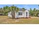 Charming home featuring a well-kept lawn and a white exterior, complemented by vibrant palm trees at 725 Avenue B Sw, Winter Haven, FL 33880