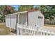 Exterior shot of a detached metal garage with a roll-up door, framed by a classic white picket fence at 725 Avenue B Sw, Winter Haven, FL 33880
