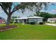 Charming single-story home with a manicured lawn, mature tree, and welcoming curb appeal on a sunny day at 8760 Plantation Ridge Blvd, Lakeland, FL 33809