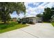 Home exterior with concrete driveway, attached garage, manicured lawn, and mature trees at 8760 Plantation Ridge Blvd, Lakeland, FL 33809