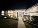 Night view of the front door and walkway beautifully lit with landscape lighting and manicured plantings at 8760 Plantation Ridge Blvd, Lakeland, FL 33809
