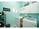 Bright laundry room featuring modern washer and dryer, storage cabinets, and decorative accents at 8760 Plantation Ridge Blvd, Lakeland, FL 33809