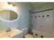 Bright bathroom with oval mirror, white vanity, toilet, and a shower-tub combo with decorative tile accents at 9093 S Bay Dr, Haines City, FL 33844