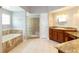 Bathroom featuring dual sinks, a soaking tub, and a separate shower with glass blocks at 9093 S Bay Dr, Haines City, FL 33844