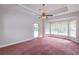 Bright bedroom with bay windows, tray ceiling, fan, and door to the outside at 9093 S Bay Dr, Haines City, FL 33844