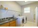 Functional laundry room including a sink, counter space, shelving, and modern washer/dryer at 9093 S Bay Dr, Haines City, FL 33844