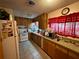 Practical kitchen with white appliances, wood cabinetry, and tile floor at 1208 Lowry Ave, Haines City, FL 33844
