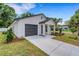 Exterior of a white single-story home featuring a gray garage door and well-manicured lawn at 1246 Dorothy St, Lakeland, FL 33815