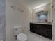 Modern bathroom features dark vanity with marble countertop, gray tile and decorative lighting at 1415 Southern Ave, Lakeland, FL 33803