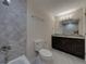 Well-lit bathroom features dark vanity with marble countertop, gray tile, and tub shower combination at 1415 Southern Ave, Lakeland, FL 33803