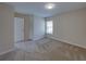 A bright bedroom featuring neutral walls, carpet, a window, and a white door at 1415 Southern Ave, Lakeland, FL 33803