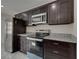 Kitchen featuring stainless-steel appliances, granite countertops, dark wood cabinets, and gray tile floors at 1415 Southern Ave, Lakeland, FL 33803