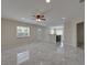 Bright living room with neutral walls, a ceiling fan, and gray tile floors flowing into an open-concept kitchen at 1415 Southern Ave, Lakeland, FL 33803