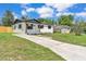 Charming one-story home featuring white siding, dark shutters, fresh landscaping, and a long driveway at 1728 Bush Ave, Lakeland, FL 33805