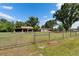 Exterior front yard view of home with metal gate, grass, and mature trees at 2145 Limedale Rd, Lakeland, FL 33809