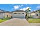 Two-car garage with decorative details and palm trees in a well-maintained front yard at 2293 Caspian Dr, Lakeland, FL 33805