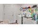 This laundry room has a washer, dryer, utility sink, and overhead shelving for storage at 2293 Caspian Dr, Lakeland, FL 33805
