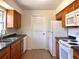 Kitchen featuring wood cabinets, white appliances, a double sink, and tile floors at 2323 Ridgeview Dr, Lakeland, FL 33810