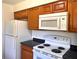 Kitchen featuring wood cabinets, white appliances, dark countertops, and tile floors at 2323 Ridgeview Dr, Lakeland, FL 33810
