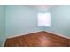 A quaint bedroom featuring wood-look floors and a single window adorned with sheer white curtains at 2710 Fairmount Ave, Lakeland, FL 33803