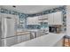 Cozy kitchen with stainless steel refrigerator, white countertops, and vintage floral wallpaper at 30 Aspen Dr # 30, Haines City, FL 33844